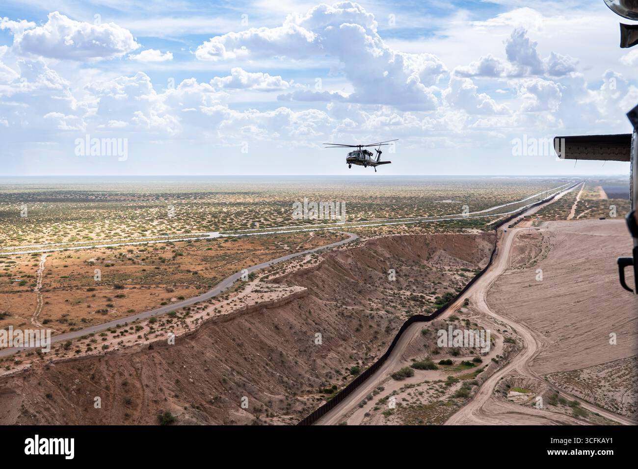 Il segretario del Dipartimento per la sicurezza interna (DHS) Kristi Noem ha viaggiato su un jet militare e poi su un elicottero fino al muro del confine meridionale degli Stati Uniti, dove ha in mano una foto - sotto la direzione del presidente Donald Trump - per dipingere il muro d'acciaio del confine nero a Santa Teresa, New Mexico. Noem è stato assistito da membri in uniforme degli agenti della dogana e della protezione delle frontiere degli Stati Uniti. La vernice nera doveva raccogliere l’energia del sole per rendere l’acciaio del muro più caldo al tatto – quindi più difficile per i clandestini scalare. La vernice, tuttavia, veniva applicata solo sul lato statunitense del muro di confine. Foto Stock