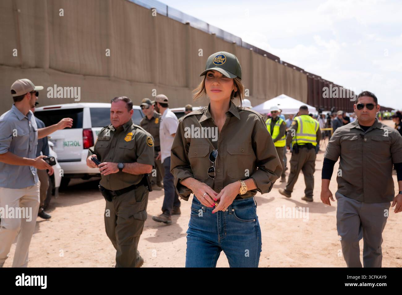 Il segretario del Dipartimento per la sicurezza interna (DHS) Kristi Noem ha viaggiato su un jet militare e poi su un elicottero fino al muro del confine meridionale degli Stati Uniti, dove ha in mano una foto - sotto la direzione del presidente Donald Trump - per dipingere il muro d'acciaio del confine nero a Santa Teresa, New Mexico. Noem è stato assistito da membri in uniforme degli agenti della dogana e della protezione delle frontiere degli Stati Uniti. La vernice nera doveva raccogliere l’energia del sole per rendere l’acciaio del muro più caldo al tatto – quindi più difficile per i clandestini scalare. La vernice, tuttavia, veniva applicata solo sul lato statunitense del muro di confine. Foto Stock