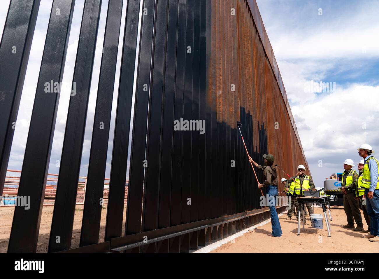 Il segretario del Dipartimento per la sicurezza interna (DHS) Kristi Noem ha viaggiato su un jet militare e poi su un elicottero fino al muro del confine meridionale degli Stati Uniti, dove ha in mano una foto - sotto la direzione del presidente Donald Trump - per dipingere il muro d'acciaio del confine nero a Santa Teresa, New Mexico. Noem è stato assistito da membri in uniforme degli agenti della dogana e della protezione delle frontiere degli Stati Uniti. La vernice nera doveva raccogliere l’energia del sole per rendere l’acciaio del muro più caldo al tatto – quindi più difficile per i clandestini scalare. La vernice, tuttavia, veniva applicata solo sul lato statunitense del muro di confine. Foto Stock