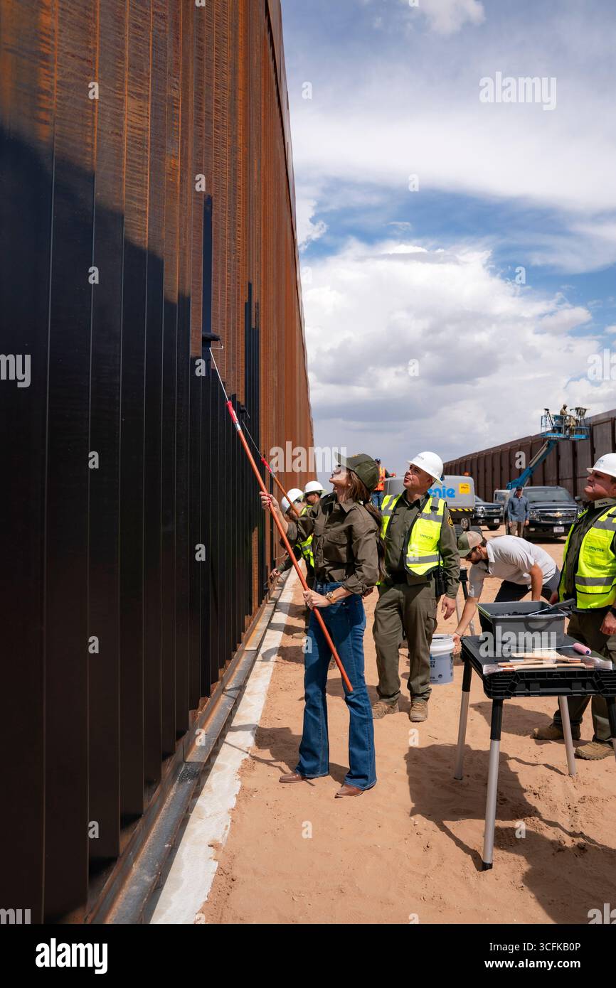 Il segretario del Dipartimento per la sicurezza interna (DHS) Kristi Noem ha viaggiato su un jet militare e poi su un elicottero fino al muro del confine meridionale degli Stati Uniti, dove ha in mano una foto - sotto la direzione del presidente Donald Trump - per dipingere il muro d'acciaio del confine nero a Santa Teresa, New Mexico. Noem è stato assistito da membri in uniforme degli agenti della dogana e della protezione delle frontiere degli Stati Uniti. La vernice nera doveva raccogliere l’energia del sole per rendere l’acciaio del muro più caldo al tatto – quindi più difficile per i clandestini scalare. La vernice, tuttavia, veniva applicata solo sul lato statunitense del muro di confine. Foto Stock