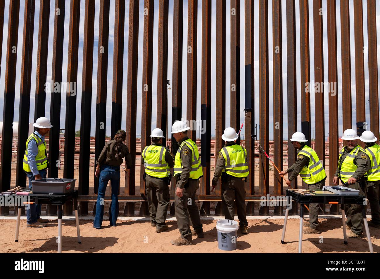 Il segretario del Dipartimento per la sicurezza interna (DHS) Kristi Noem ha viaggiato su un jet militare e poi su un elicottero fino al muro del confine meridionale degli Stati Uniti, dove ha in mano una foto - sotto la direzione del presidente Donald Trump - per dipingere il muro d'acciaio del confine nero a Santa Teresa, New Mexico. Noem è stato assistito da membri in uniforme degli agenti della dogana e della protezione delle frontiere degli Stati Uniti. La vernice nera doveva raccogliere l’energia del sole per rendere l’acciaio del muro più caldo al tatto – quindi più difficile per i clandestini scalare. La vernice, tuttavia, veniva applicata solo sul lato statunitense del muro di confine. Foto Stock