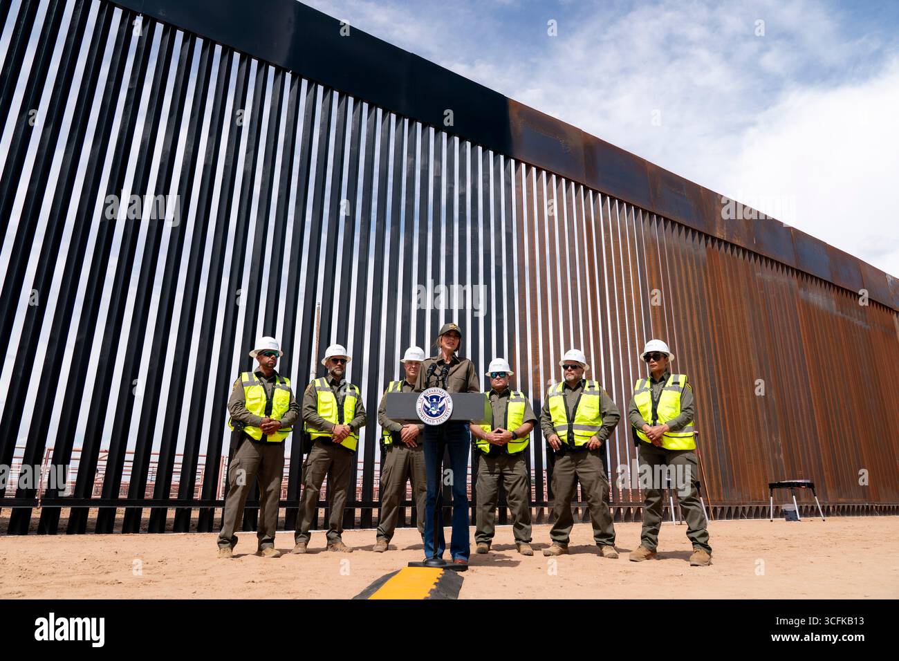 Il segretario del Dipartimento per la sicurezza interna (DHS) Kristi Noem ha viaggiato su un jet militare e poi su un elicottero fino al muro del confine meridionale degli Stati Uniti, dove ha in mano una foto - sotto la direzione del presidente Donald Trump - per dipingere il muro d'acciaio del confine nero a Santa Teresa, New Mexico. Noem è stato assistito da membri in uniforme degli agenti della dogana e della protezione delle frontiere degli Stati Uniti. La vernice nera doveva raccogliere l’energia del sole per rendere l’acciaio del muro più caldo al tatto – quindi più difficile per i clandestini scalare. La vernice, tuttavia, veniva applicata solo sul lato statunitense del muro di confine. Foto Stock