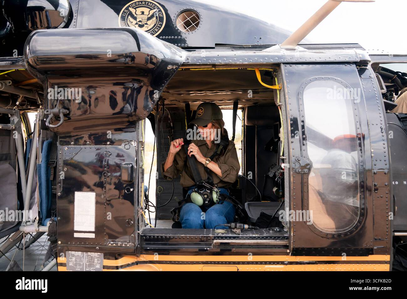 Il segretario del Dipartimento per la sicurezza interna (DHS) Kristi Noem ha viaggiato su un jet militare e poi su un elicottero fino al muro del confine meridionale degli Stati Uniti, dove ha in mano una foto - sotto la direzione del presidente Donald Trump - per dipingere il muro d'acciaio del confine nero a Santa Teresa, New Mexico. Noem è stato assistito da membri in uniforme degli agenti della dogana e della protezione delle frontiere degli Stati Uniti. La vernice nera doveva raccogliere l’energia del sole per rendere l’acciaio del muro più caldo al tatto – quindi più difficile per i clandestini scalare. La vernice, tuttavia, veniva applicata solo sul lato statunitense del muro di confine. Foto Stock