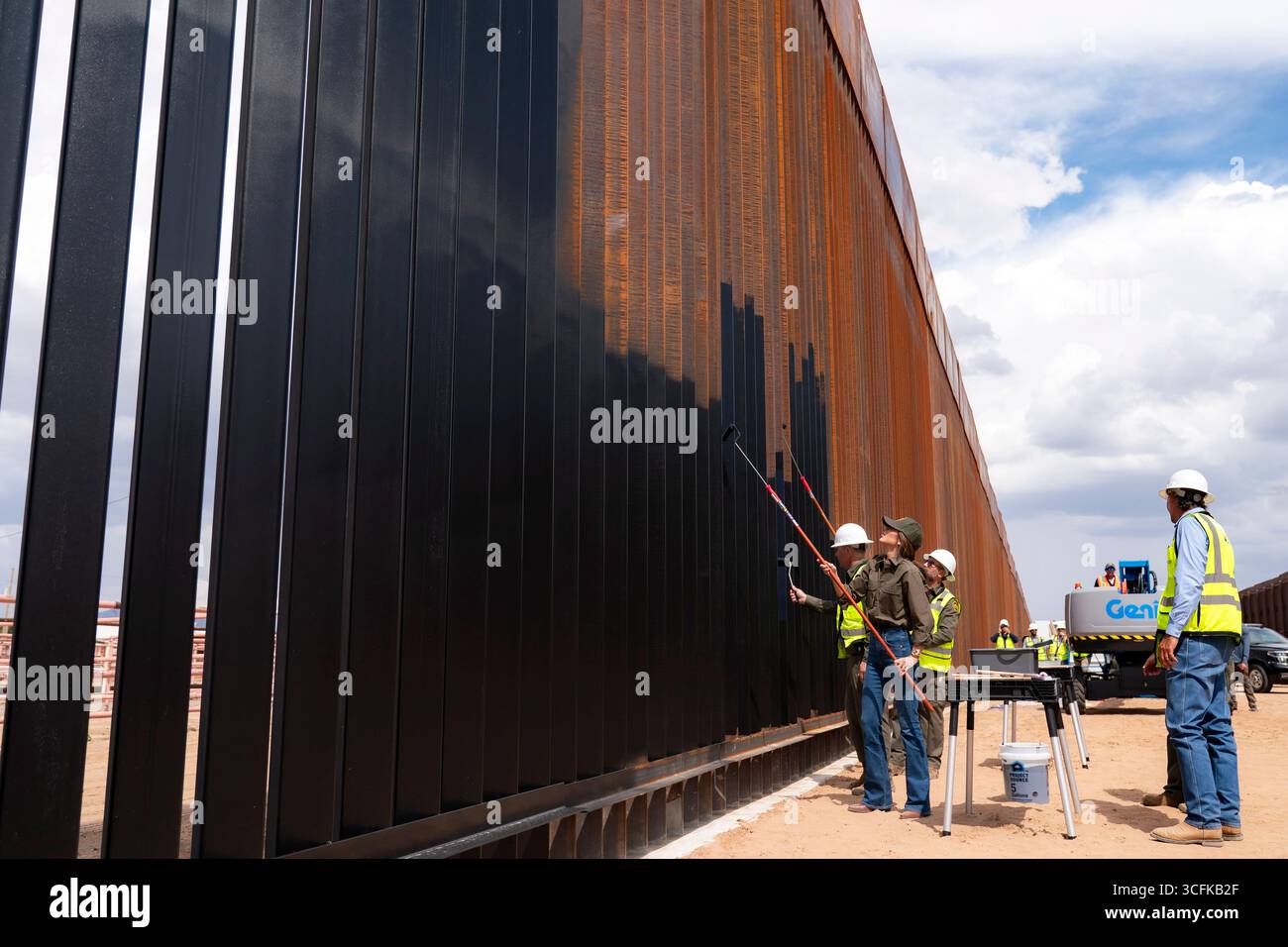 Il segretario del Dipartimento per la sicurezza interna (DHS) Kristi Noem ha viaggiato su un jet militare e poi su un elicottero fino al muro del confine meridionale degli Stati Uniti, dove ha in mano una foto - sotto la direzione del presidente Donald Trump - per dipingere il muro d'acciaio del confine nero a Santa Teresa, New Mexico. Noem è stato assistito da membri in uniforme degli agenti della dogana e della protezione delle frontiere degli Stati Uniti. La vernice nera doveva raccogliere l’energia del sole per rendere l’acciaio del muro più caldo al tatto – quindi più difficile per i clandestini scalare. La vernice, tuttavia, veniva applicata solo sul lato statunitense del muro di confine. Foto Stock