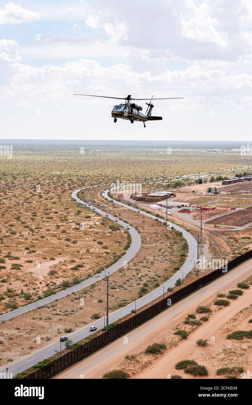 Il segretario del Dipartimento per la sicurezza interna (DHS) Kristi Noem ha viaggiato su un jet militare e poi su un elicottero fino al muro del confine meridionale degli Stati Uniti, dove ha in mano una foto - sotto la direzione del presidente Donald Trump - per dipingere il muro d'acciaio del confine nero a Santa Teresa, New Mexico. Noem è stato assistito da membri in uniforme degli agenti della dogana e della protezione delle frontiere degli Stati Uniti. La vernice nera doveva raccogliere l’energia del sole per rendere l’acciaio del muro più caldo al tatto – quindi più difficile per i clandestini scalare. La vernice, tuttavia, veniva applicata solo sul lato statunitense del muro di confine. Foto Stock