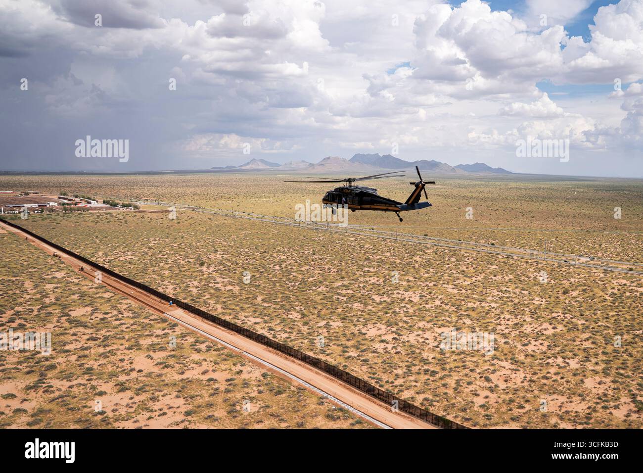 Il segretario del Dipartimento per la sicurezza interna (DHS) Kristi Noem ha viaggiato su un jet militare e poi su un elicottero fino al muro del confine meridionale degli Stati Uniti, dove ha in mano una foto - sotto la direzione del presidente Donald Trump - per dipingere il muro d'acciaio del confine nero a Santa Teresa, New Mexico. Noem è stato assistito da membri in uniforme degli agenti della dogana e della protezione delle frontiere degli Stati Uniti. La vernice nera doveva raccogliere l’energia del sole per rendere l’acciaio del muro più caldo al tatto – quindi più difficile per i clandestini scalare. La vernice, tuttavia, veniva applicata solo sul lato statunitense del muro di confine. Foto Stock