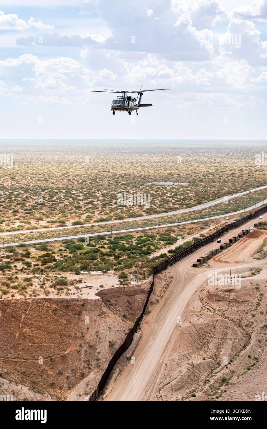 Il segretario del Dipartimento per la sicurezza interna (DHS) Kristi Noem ha viaggiato su un jet militare e poi su un elicottero fino al muro del confine meridionale degli Stati Uniti, dove ha in mano una foto - sotto la direzione del presidente Donald Trump - per dipingere il muro d'acciaio del confine nero a Santa Teresa, New Mexico. Noem è stato assistito da membri in uniforme degli agenti della dogana e della protezione delle frontiere degli Stati Uniti. La vernice nera doveva raccogliere l’energia del sole per rendere l’acciaio del muro più caldo al tatto – quindi più difficile per i clandestini scalare. La vernice, tuttavia, veniva applicata solo sul lato statunitense del muro di confine. Foto Stock