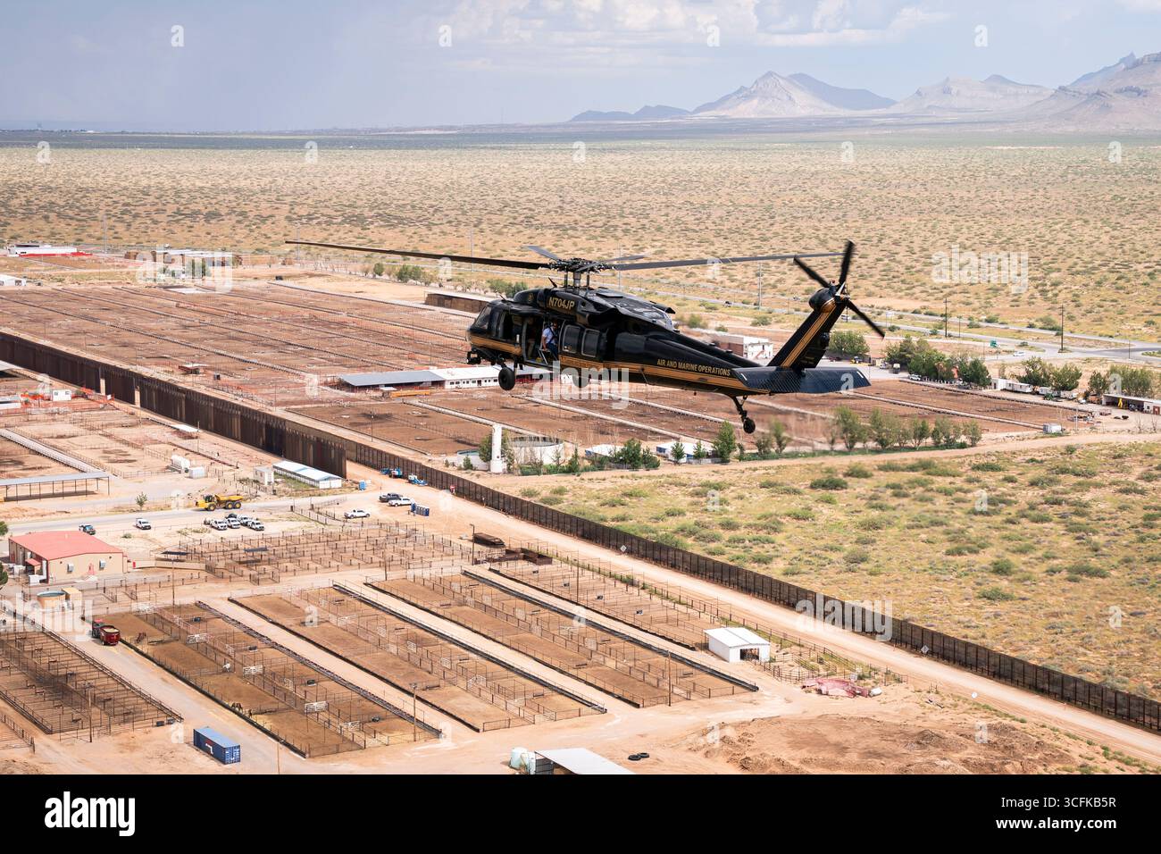 Il segretario del Dipartimento per la sicurezza interna (DHS) Kristi Noem ha viaggiato su un jet militare e poi su un elicottero fino al muro del confine meridionale degli Stati Uniti, dove ha in mano una foto - sotto la direzione del presidente Donald Trump - per dipingere il muro d'acciaio del confine nero a Santa Teresa, New Mexico. Noem è stato assistito da membri in uniforme degli agenti della dogana e della protezione delle frontiere degli Stati Uniti. La vernice nera doveva raccogliere l’energia del sole per rendere l’acciaio del muro più caldo al tatto – quindi più difficile per i clandestini scalare. La vernice, tuttavia, veniva applicata solo sul lato statunitense del muro di confine. Foto Stock