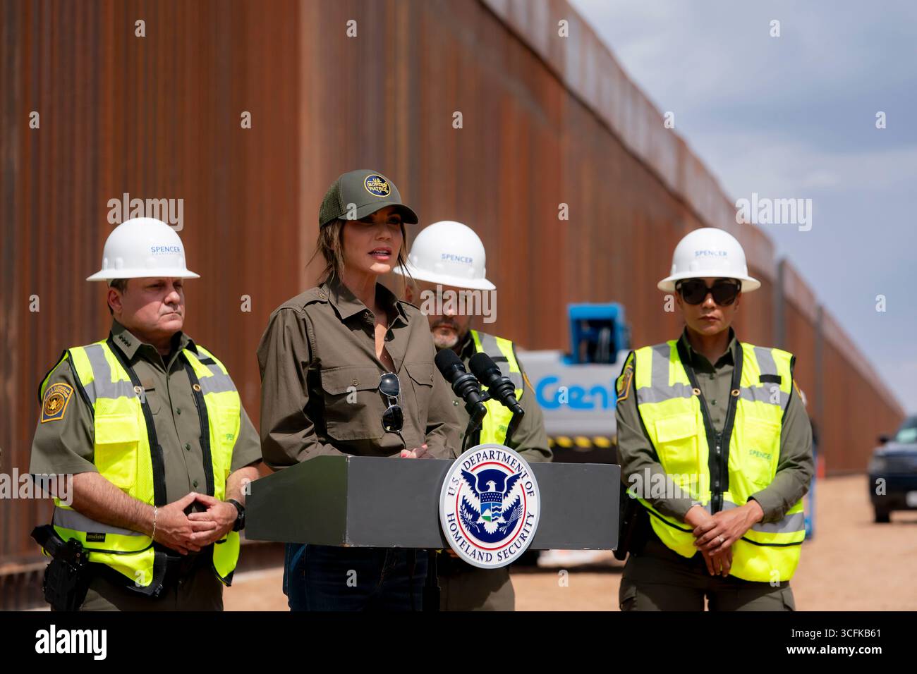 Il segretario del Dipartimento per la sicurezza interna (DHS) Kristi Noem ha viaggiato su un jet militare e poi su un elicottero fino al muro del confine meridionale degli Stati Uniti, dove ha in mano una foto - sotto la direzione del presidente Donald Trump - per dipingere il muro d'acciaio del confine nero a Santa Teresa, New Mexico. Noem è stato assistito da membri in uniforme degli agenti della dogana e della protezione delle frontiere degli Stati Uniti. La vernice nera doveva raccogliere l’energia del sole per rendere l’acciaio del muro più caldo al tatto – quindi più difficile per i clandestini scalare. La vernice, tuttavia, veniva applicata solo sul lato statunitense del muro di confine. Foto Stock
