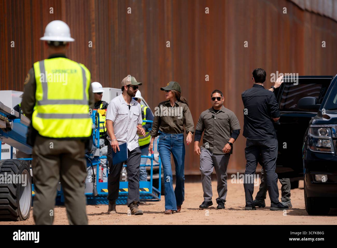 Il segretario del Dipartimento per la sicurezza interna (DHS) Kristi Noem ha viaggiato su un jet militare e poi su un elicottero fino al muro del confine meridionale degli Stati Uniti, dove ha in mano una foto - sotto la direzione del presidente Donald Trump - per dipingere il muro d'acciaio del confine nero a Santa Teresa, New Mexico. Noem è stato assistito da membri in uniforme degli agenti della dogana e della protezione delle frontiere degli Stati Uniti. La vernice nera doveva raccogliere l’energia del sole per rendere l’acciaio del muro più caldo al tatto – quindi più difficile per i clandestini scalare. La vernice, tuttavia, veniva applicata solo sul lato statunitense del muro di confine. Foto Stock