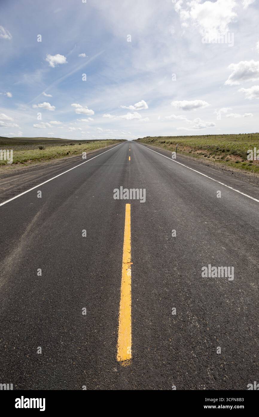 Una strada lunga e vuota con una linea gialla nel mezzo Foto Stock