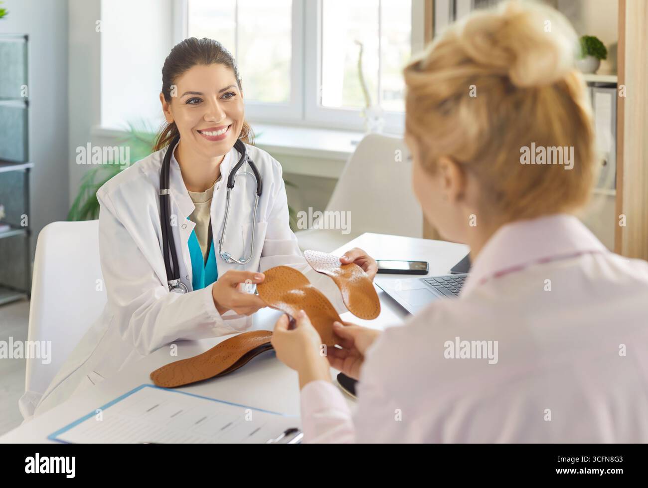 Ortopedico che offre solette ortopediche al paziente su appuntamento, con due inserti ortopedici Foto Stock