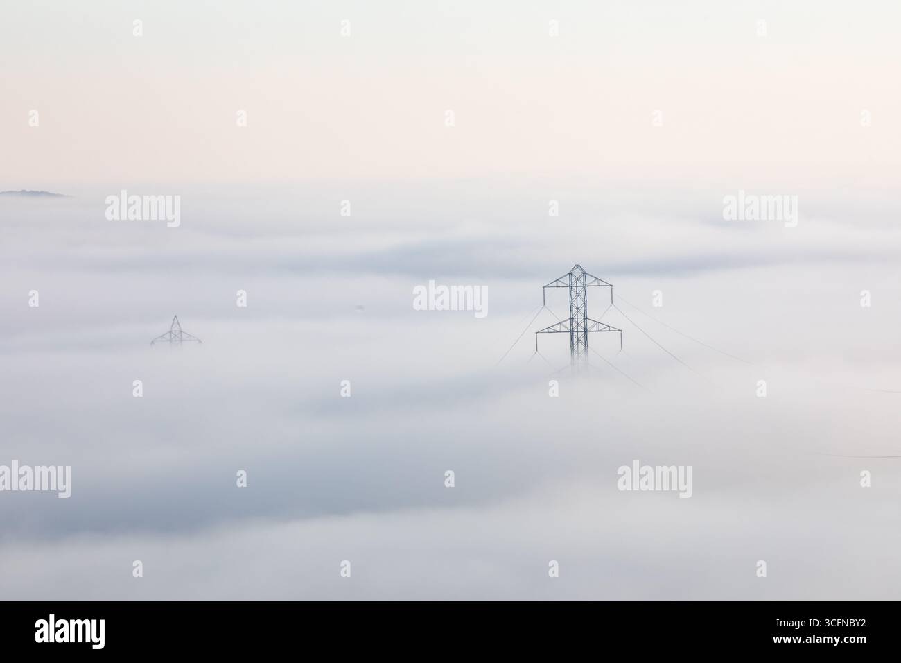 Una torre di linea elettrica è visibile nella nebbia Foto Stock