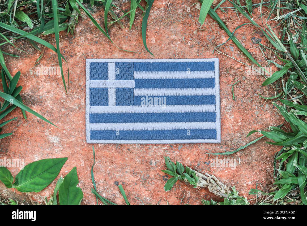 Bandiera greca ricamata ecologica su pietra antica nella natura della foresta, che simboleggia la giornata della Terra, la consapevolezza del cambiamento climatico e la calma naturale. Foto Stock