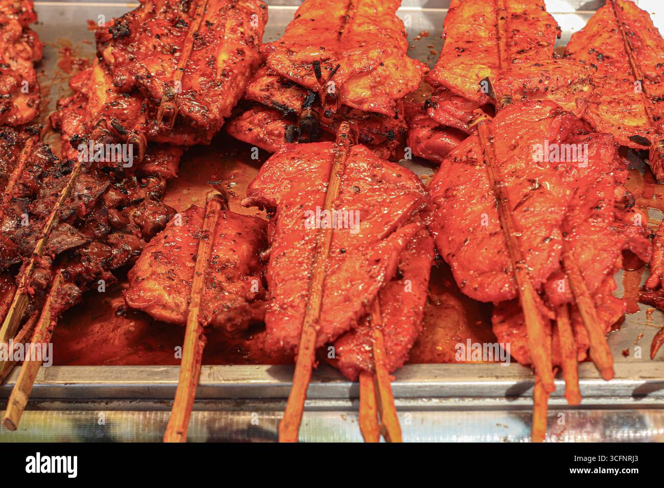 Spiedini di pollo alla griglia tradizionali tailandesi con salsa rossa, succosi e affumicati, che riflettono gli autentici sapori dello Street food dei mercati notturni. Foto Stock