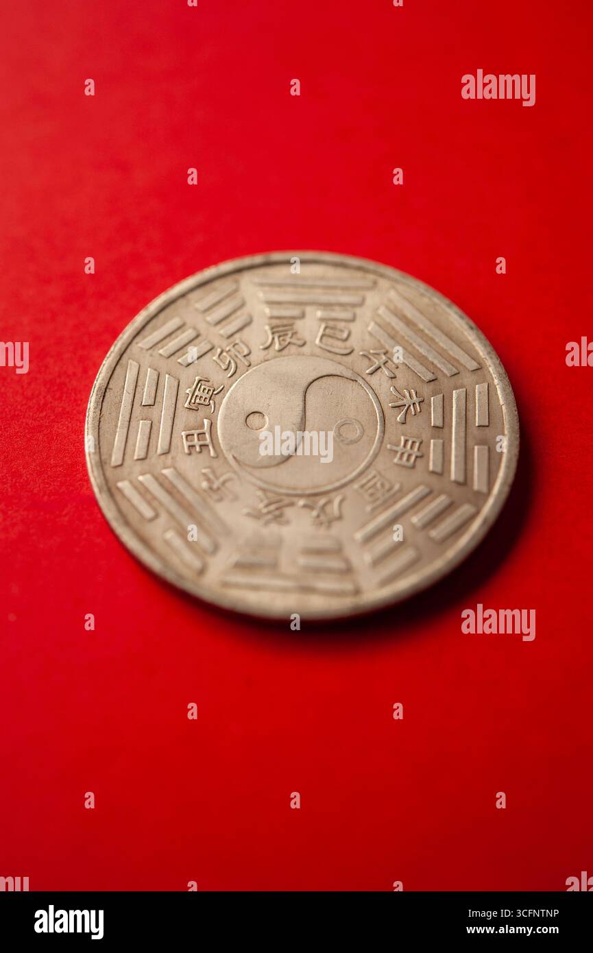 Moneta cinese Feng Shui con il simbolo Yin Yang e trigrammi Bagua su sfondo rosso Foto Stock