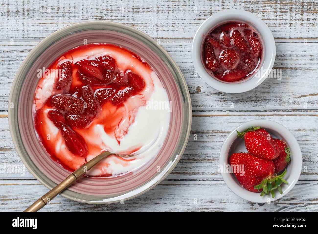 Piatto bianco con fragole rosse e yogurt naturale su un tavolo in legno, da vicino, vista dall'alto Foto Stock