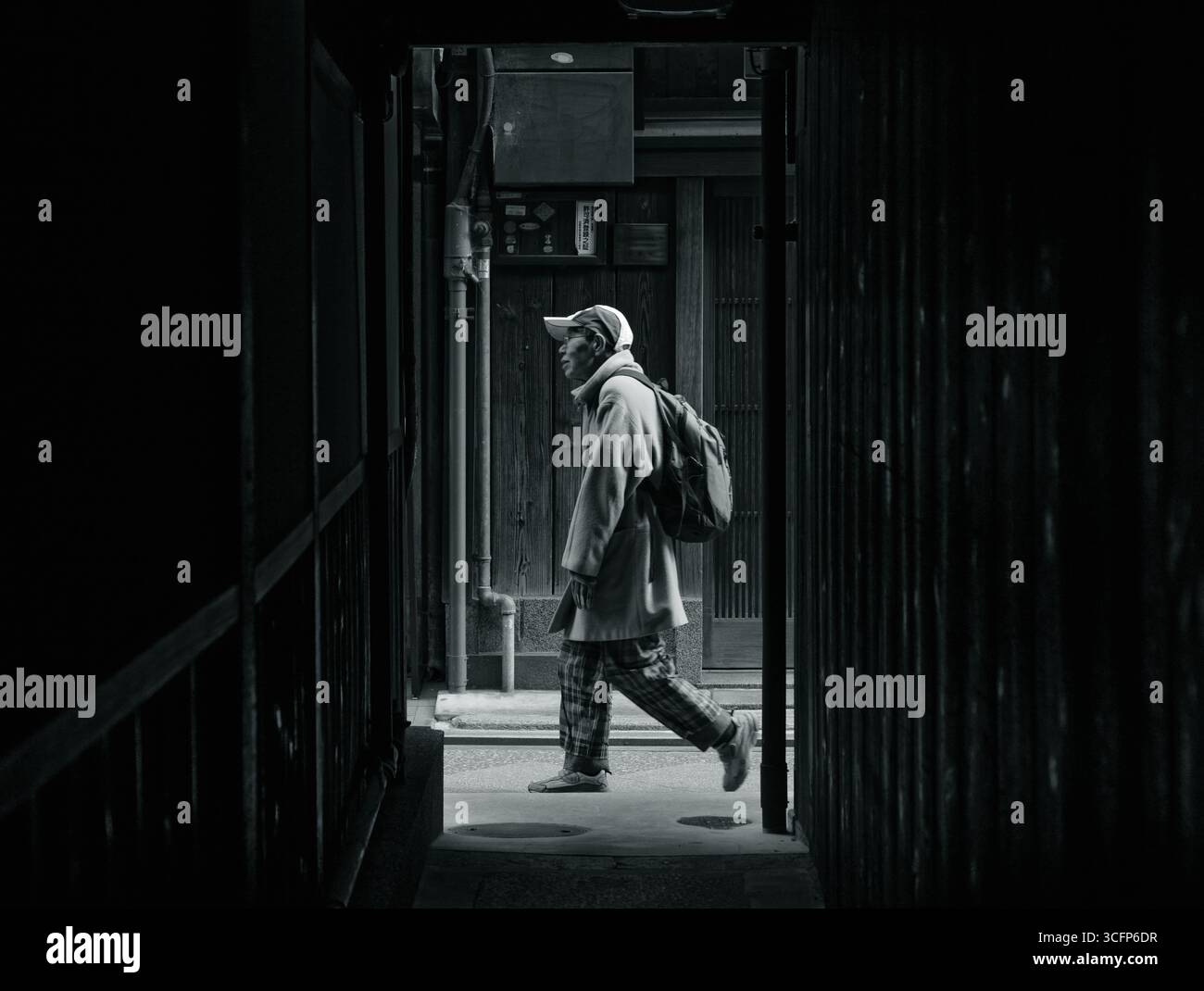 Foto in bianco e nero di un uomo con movimento sfocato che cammina attraverso gli iconici vicoli stretti del quartiere Pontocho di Kyoto Foto Stock