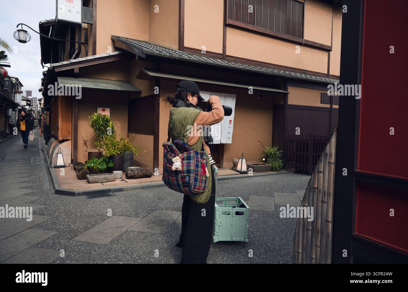 Fotografo che cattura la vita di strada nella zona di Pontocho di Kyoto, incorniciata da una tradizionale architettura in legno e stretti vicoli Foto Stock