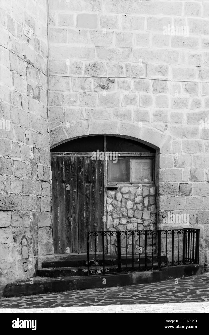 Porta rustica in legno intemprata posta contro il muro in mattoni di pietra Foto Stock