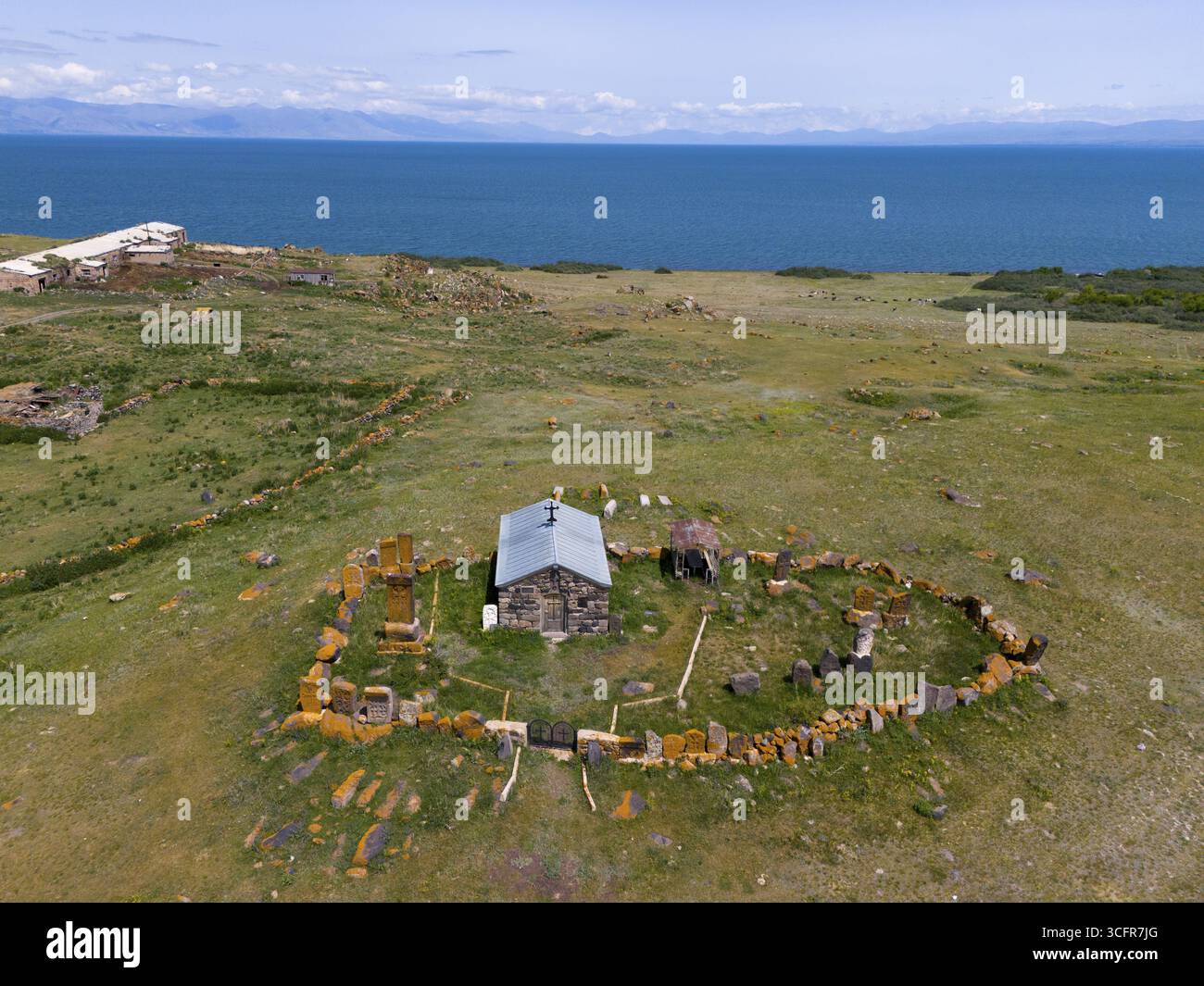 Sito Santo circondato da un vasto paesaggio costiero con un lontano lago blu, vista aerea, Cappella della Santa Croce, Sarukhan, lago Sevan, Gegharkunik Pr Foto Stock