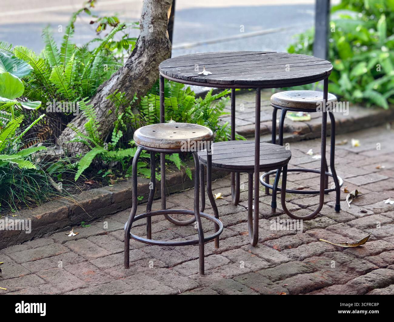 Una serie di posti a sedere all'aperto con sgabelli rotondi in legno e un tavolo rustico Foto Stock