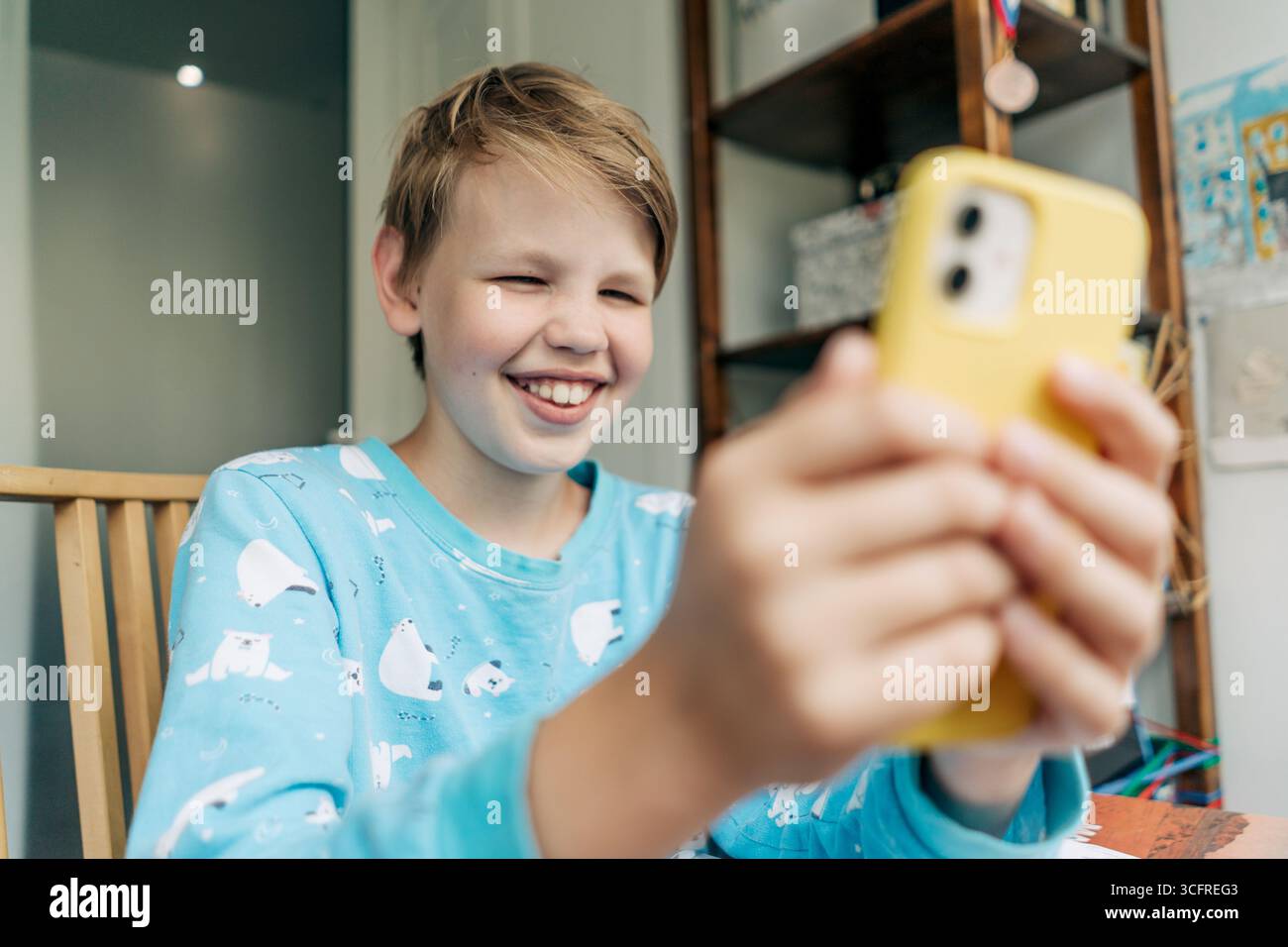 Il ragazzo di generazione alfa ridendo usa un telefono cellulare. Foto Stock