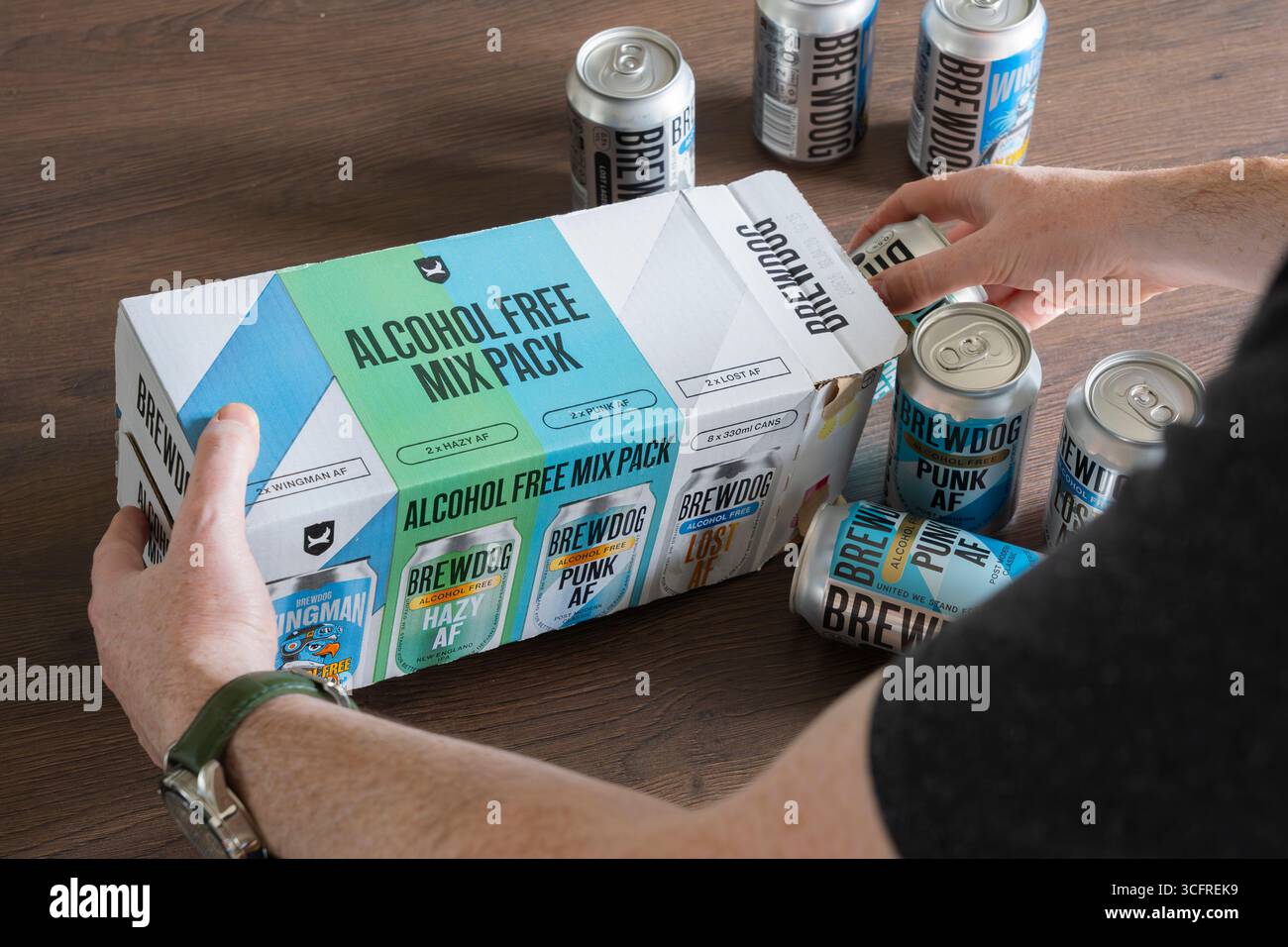 Uomo che rimuove lattine di birre artigianali BrewDog senza alcol (AF) da un mix pack a casa, Regno Unito. Concetto: Tendenze del bere, birra a basso contenuto alcolico, bere a casa Foto Stock