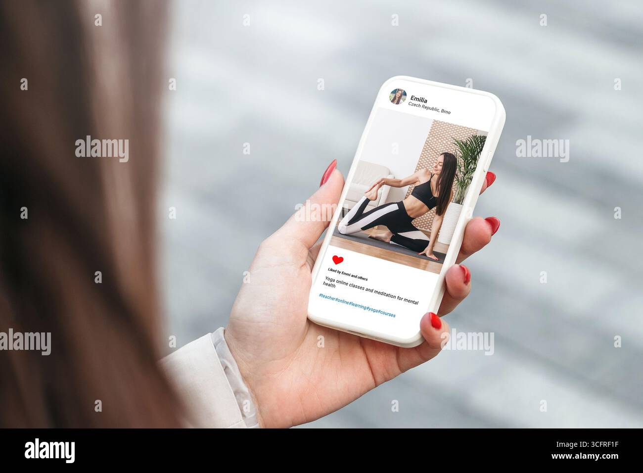 Donna che guarda la foto di una bella modella che fa yoga sul cellulare. Mano femminile che tiene la mano intelligente e sfoglia i social media Foto Stock