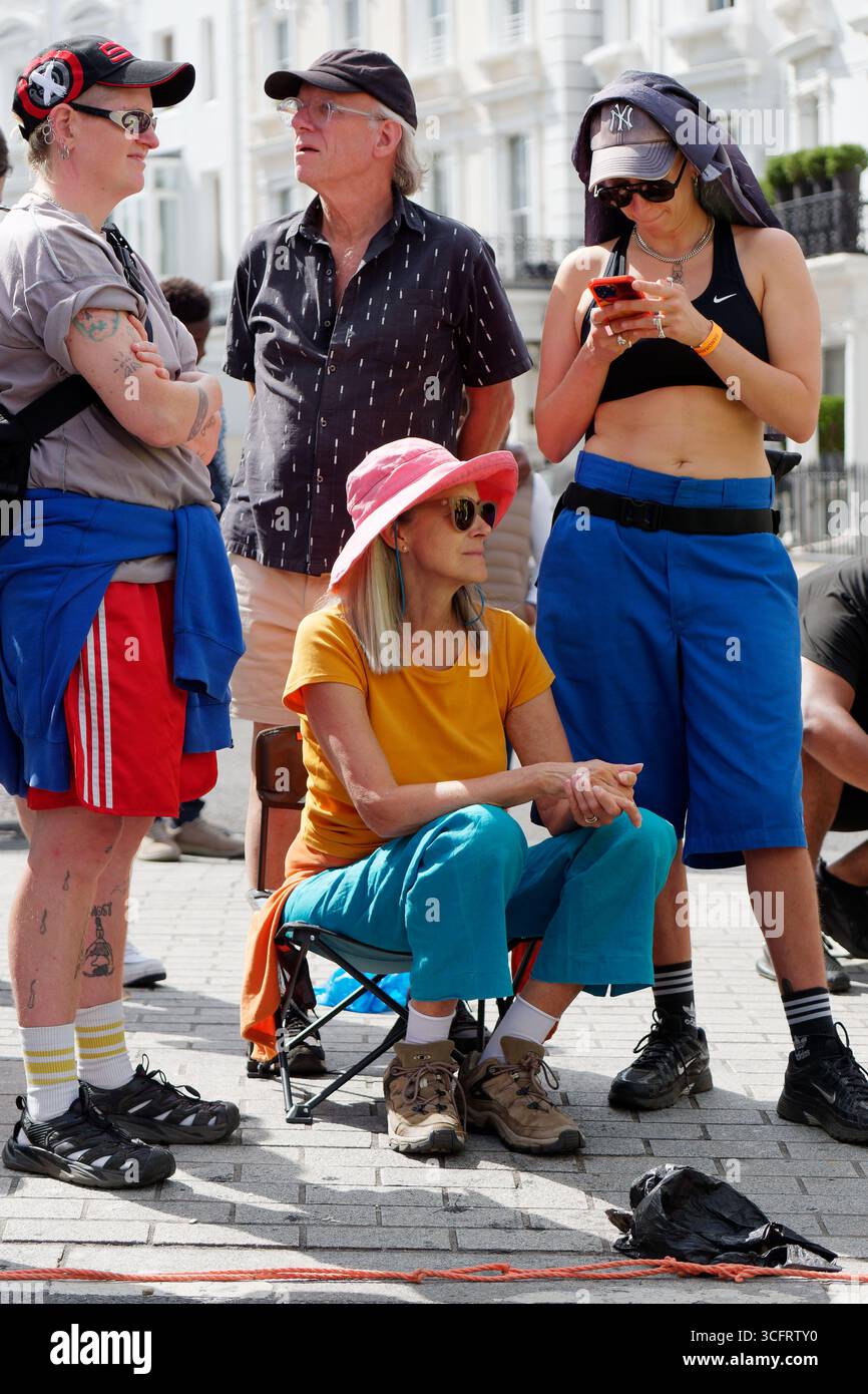 Gli spettatori anziani che indossano cappelli come una donna si siedono seduti durante il Carnevale di Notting Hill, Londra. Inghilterra 24 agosto 2025 Foto Stock