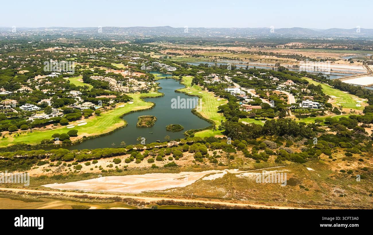 Un lago serpeggiante si snoda attraverso un quartiere esclusivo con campi da golf. Foto Stock