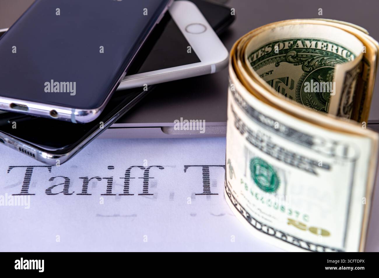 Prodotti elettronici e banconote in dollari USA su sfondo bianco con la parola "tariffa" stampata. Un concetto di imposta sulle tariffe USA. Foto Stock