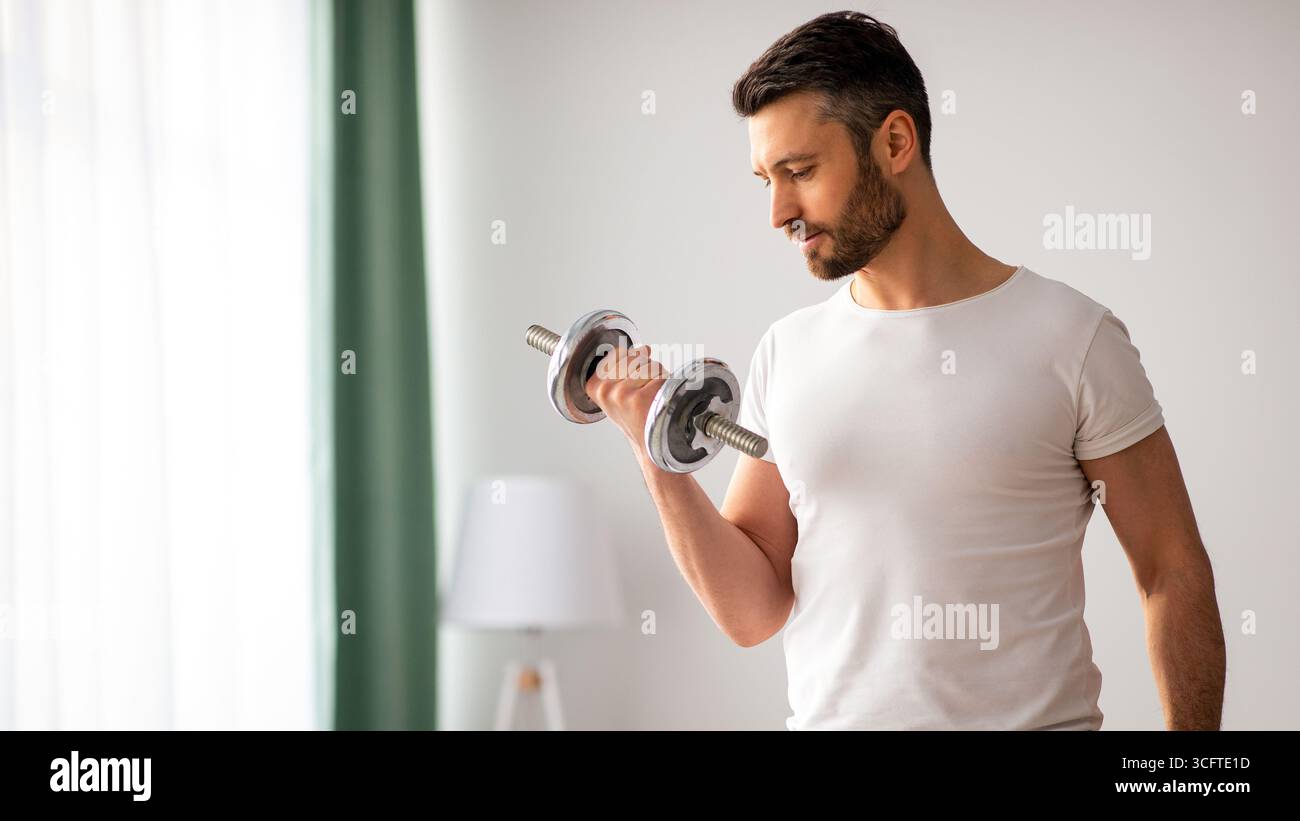 Closeup di bell'uomo bearded che fa workout dumbbell a casa Foto Stock
