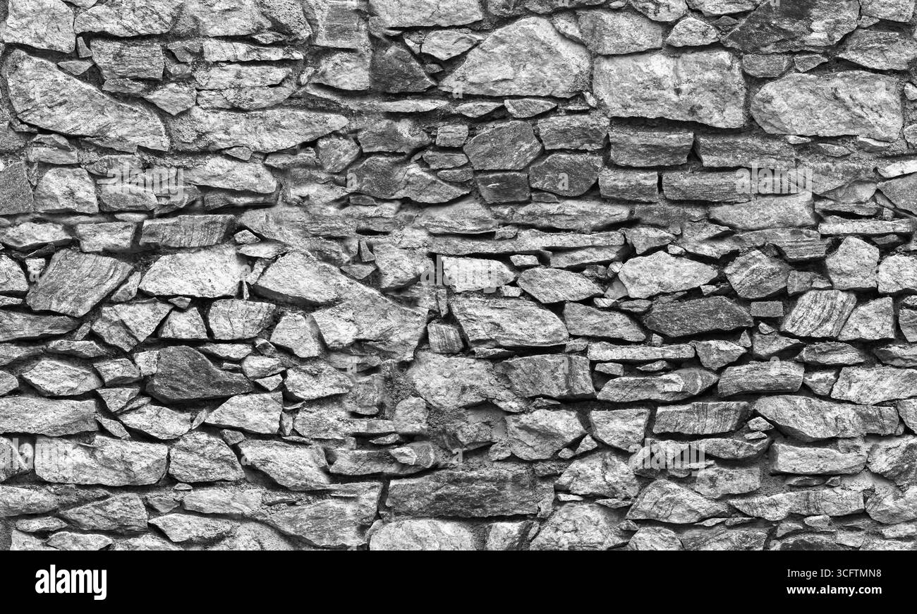 Vecchio muro in pietra grigio scuro, texture fotografica di sfondo senza cuciture, vista frontale, bianco e nero Foto Stock