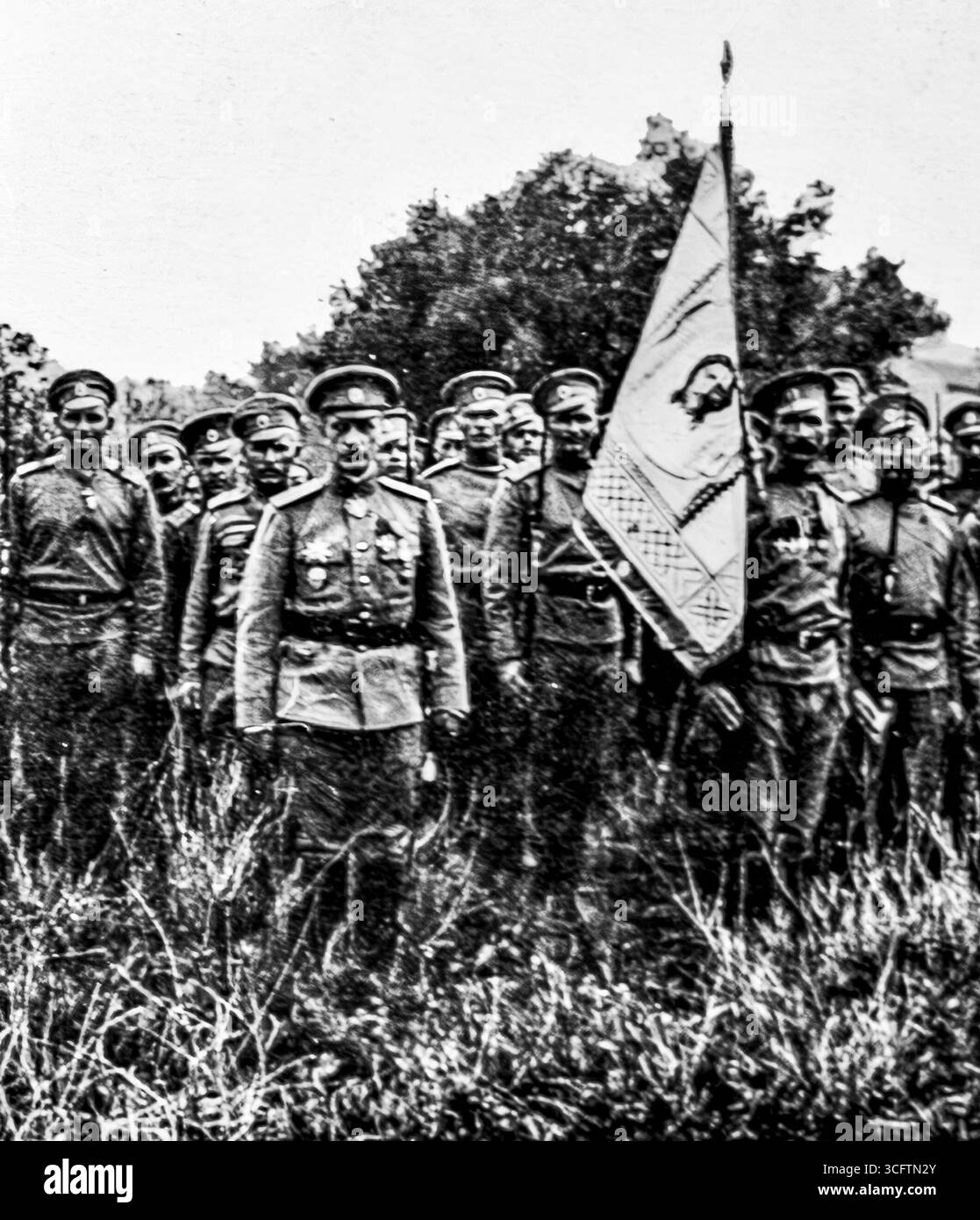 Il generale Lohvitsky e gli ufficiali russi espongono uno stendardo militare ricamato con l'immagine di Cristo e le iniziali dell'imperatore Nicola II, 1916. Questa fotografia riflette il simbolismo religioso e imperiale all'interno dell'esercito russo durante la prima guerra mondiale. Pubblicato su l’Illustration, 29 aprile 1916. Foto Stock