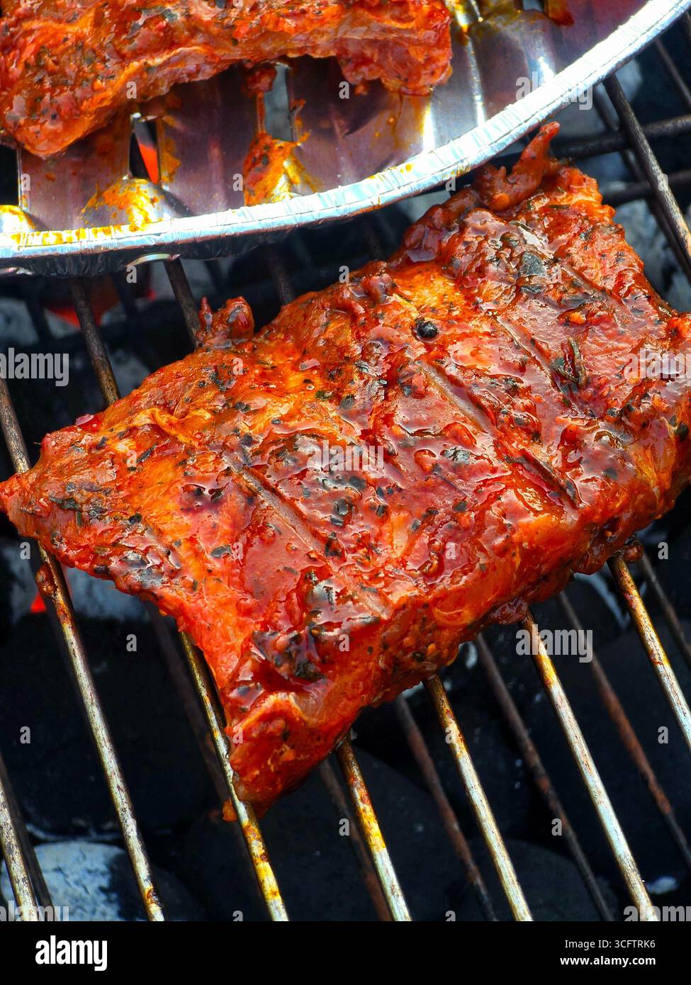 Un primo piano di un taglio spesso di costolette glassate grigliate su carbone caldo, mostrando la salsa rossa caramellata e i segni della griglia. - Immagine stock catturata con smartphone