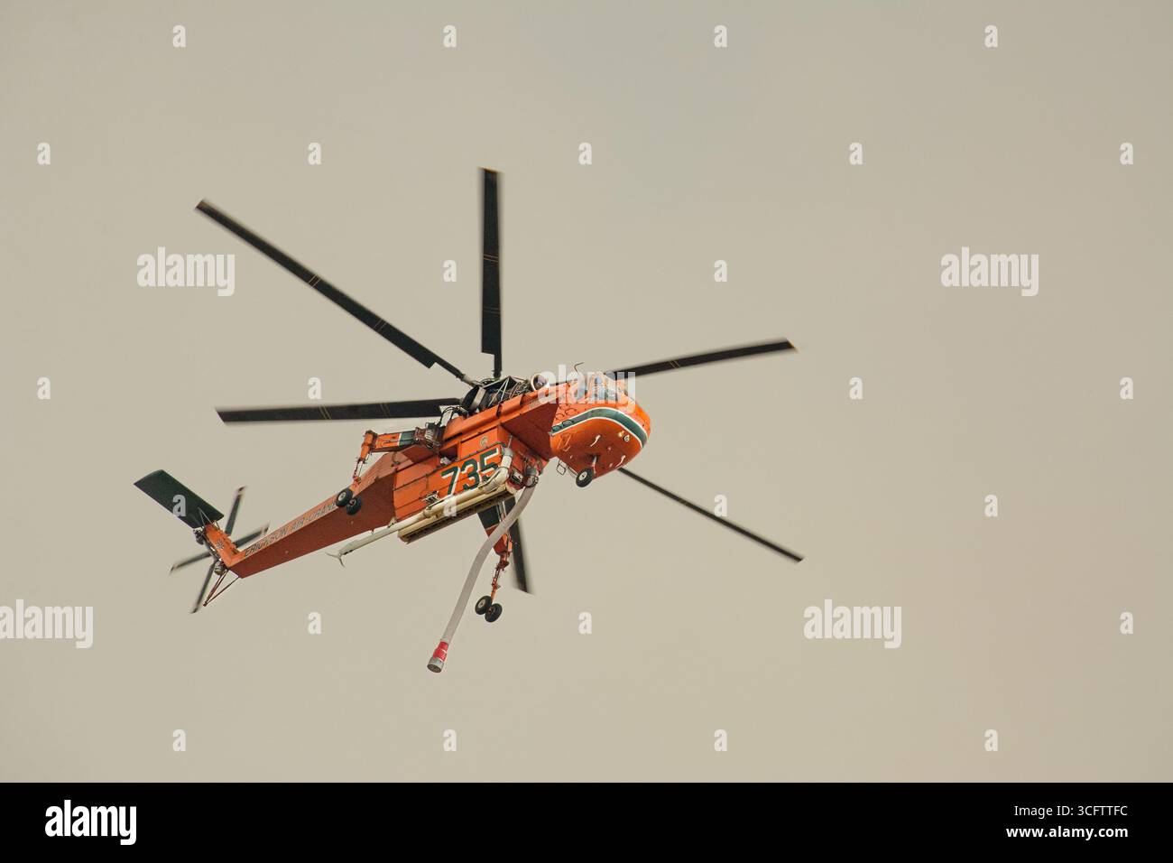Il fumo copre il cielo mentre Goliath, un elicottero Erickson Aircrane modificato, vola sopra un incendio vicino a Littlerock, California. Foto Stock