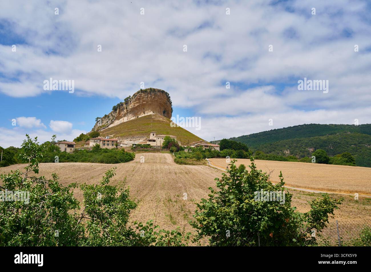 Lo splendido paesaggio della Serrania de cuenca presenta un affascinante villaggio annidato alla base di una scogliera torreggiante, creando una scena pittoresca sotto un clo Foto Stock