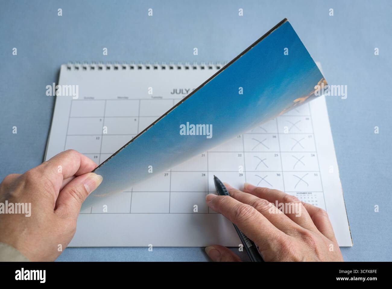 La mano di una donna che sfoglia il calendario. Concetto di pianificazione di riunioni o eventi. Foto Stock
