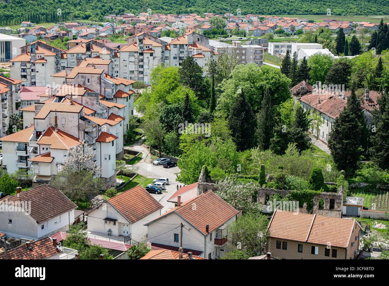 Vista aerea dei Balcani. La scena include edifici residenziali, alberi verdi e tetti di tegole rosse sotto un cielo limpido. Foto Stock