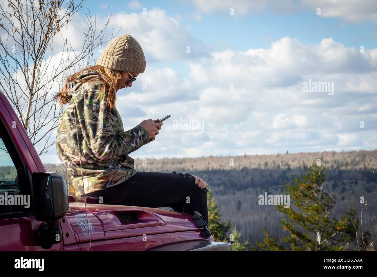 Giovane donna che usa uno smartphone in una zona remota, Biwabik, Minnesota, Stati Uniti Foto Stock