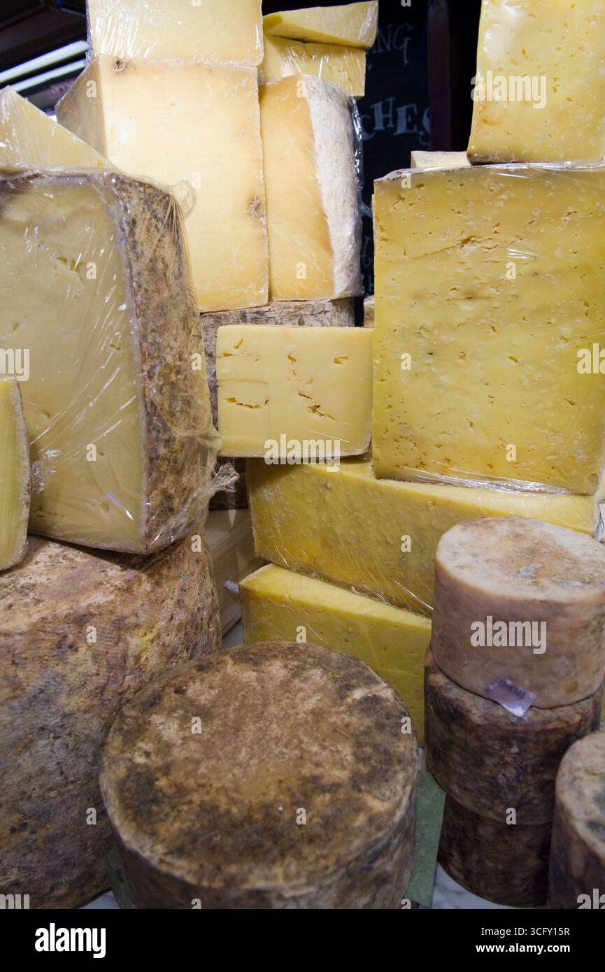 Pile di formaggi in mostra in un negozio di formaggi di Londra. Foto Stock