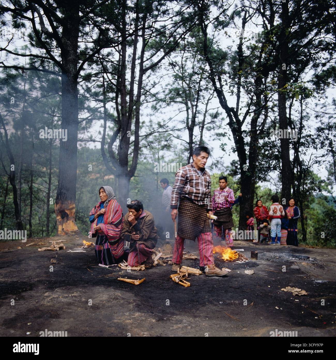 Mehrere Personen entzünden zeremonielle Feuer auf einer bewaldeten Lichtung, vermutlich im Rahmen eines traditionellen Maya-rituals. Guatemala, um 1980. Foto Stock
