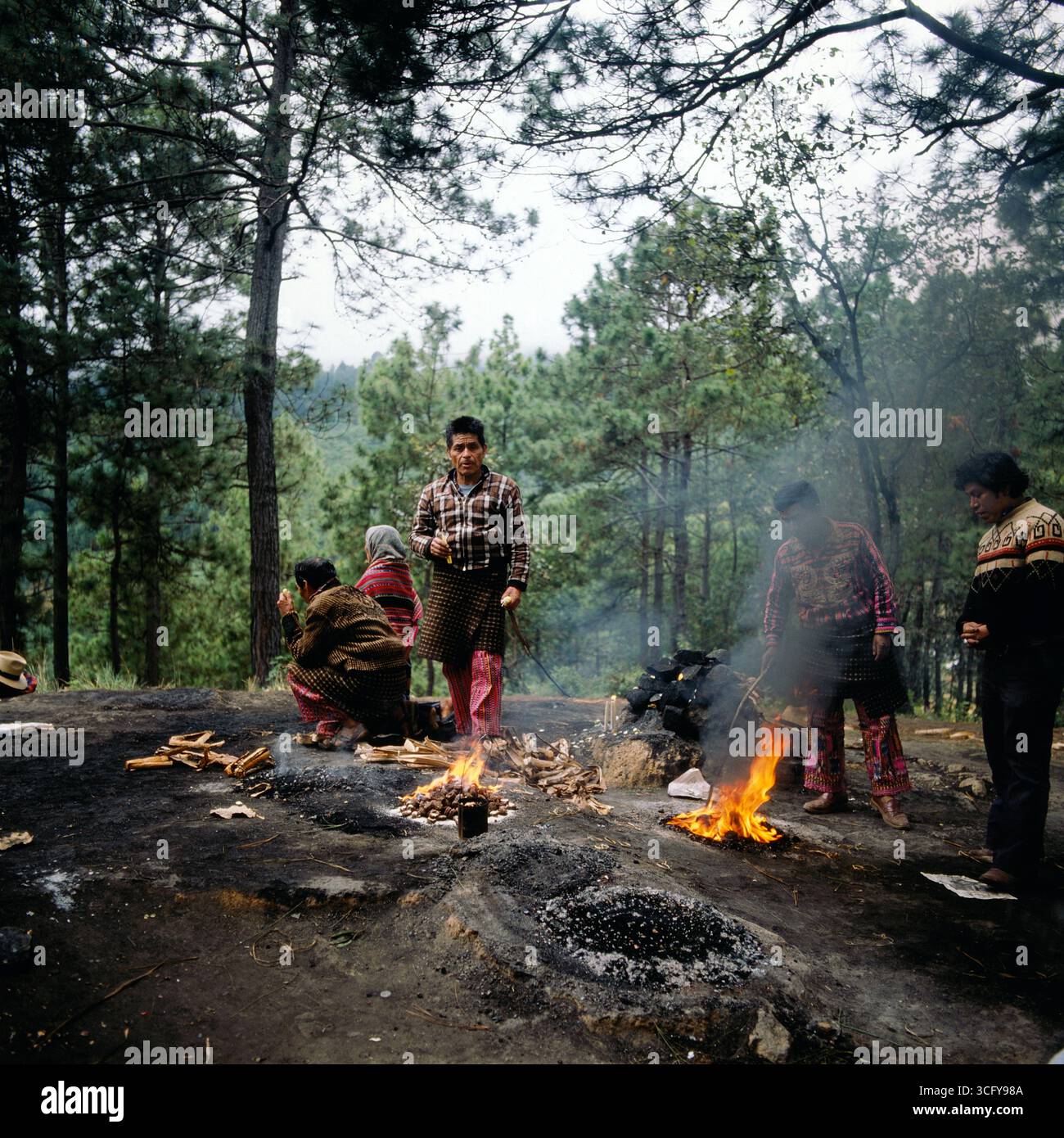 Mehrere Personen entzünden zeremonielle Feuer auf einer bewaldeten Lichtung, vermutlich im Rahmen eines traditionellen Maya-rituals. Guatemala, um 1980. Foto Stock