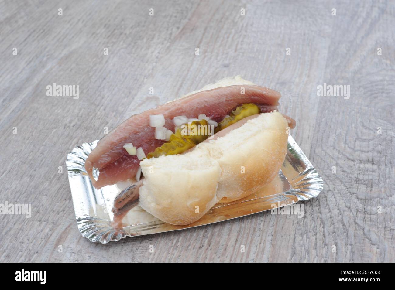 Il «Herring Sandwich» (Broodje Haring) è una prelibatezza olandese con panino bianco e aringhe crude salate, cetriolini a fette e cipolle a dadini, servito freddo Foto Stock