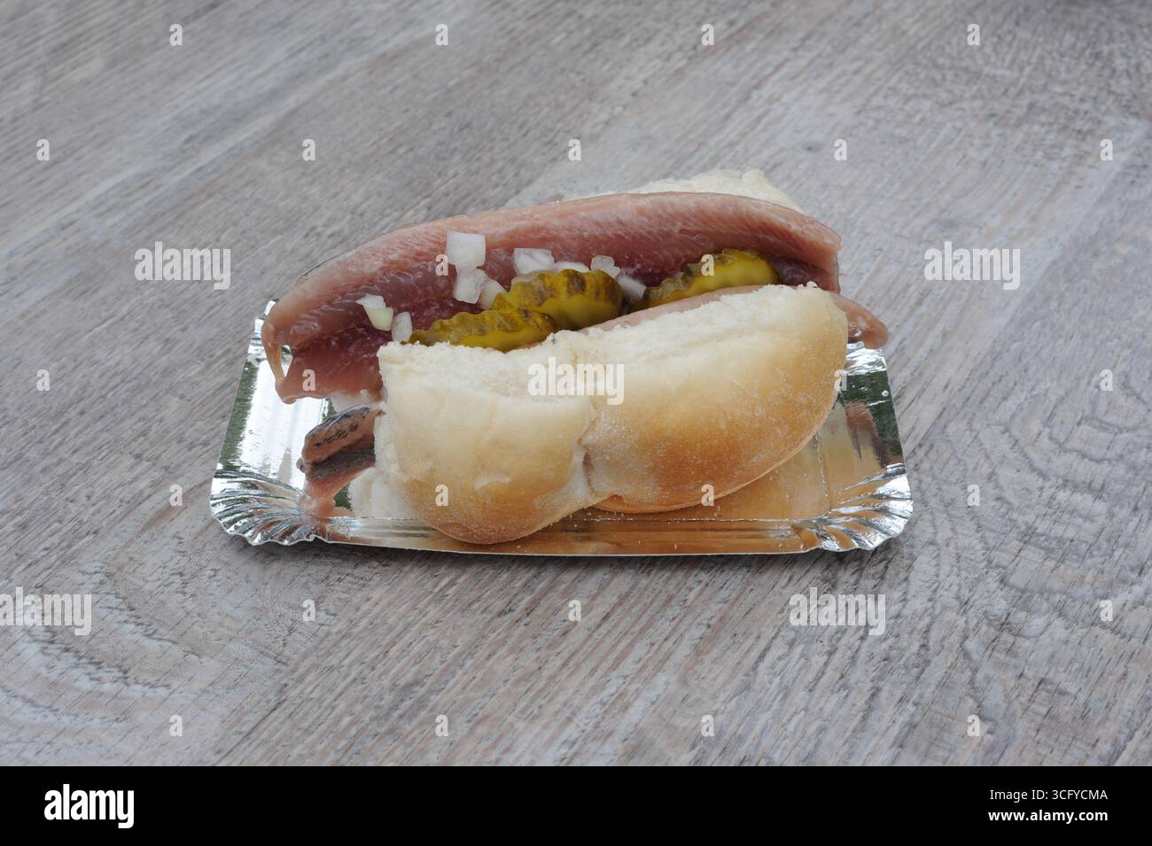 Il «Herring Sandwich» (Broodje Haring) è una prelibatezza olandese con panino bianco e aringhe crude salate, cetriolini a fette e cipolle a dadini, servito freddo Foto Stock