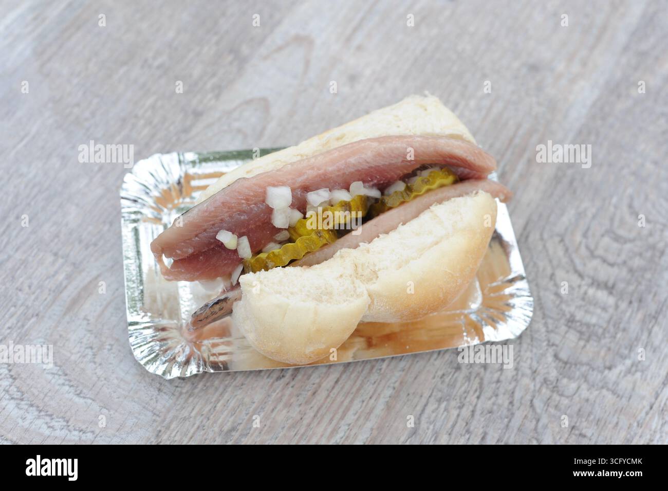 Il «Herring Sandwich» (Broodje Haring) è una prelibatezza olandese con panino bianco e aringhe crude salate, cetriolini a fette e cipolle a dadini, servito freddo Foto Stock