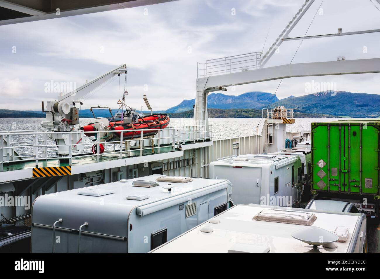 Ponte delle navi da carico pieno di auto che mostrano operazioni marittime e scenari montani panoramici, sottolineando il trasporto e la sicurezza in mare. Nordlan Foto Stock