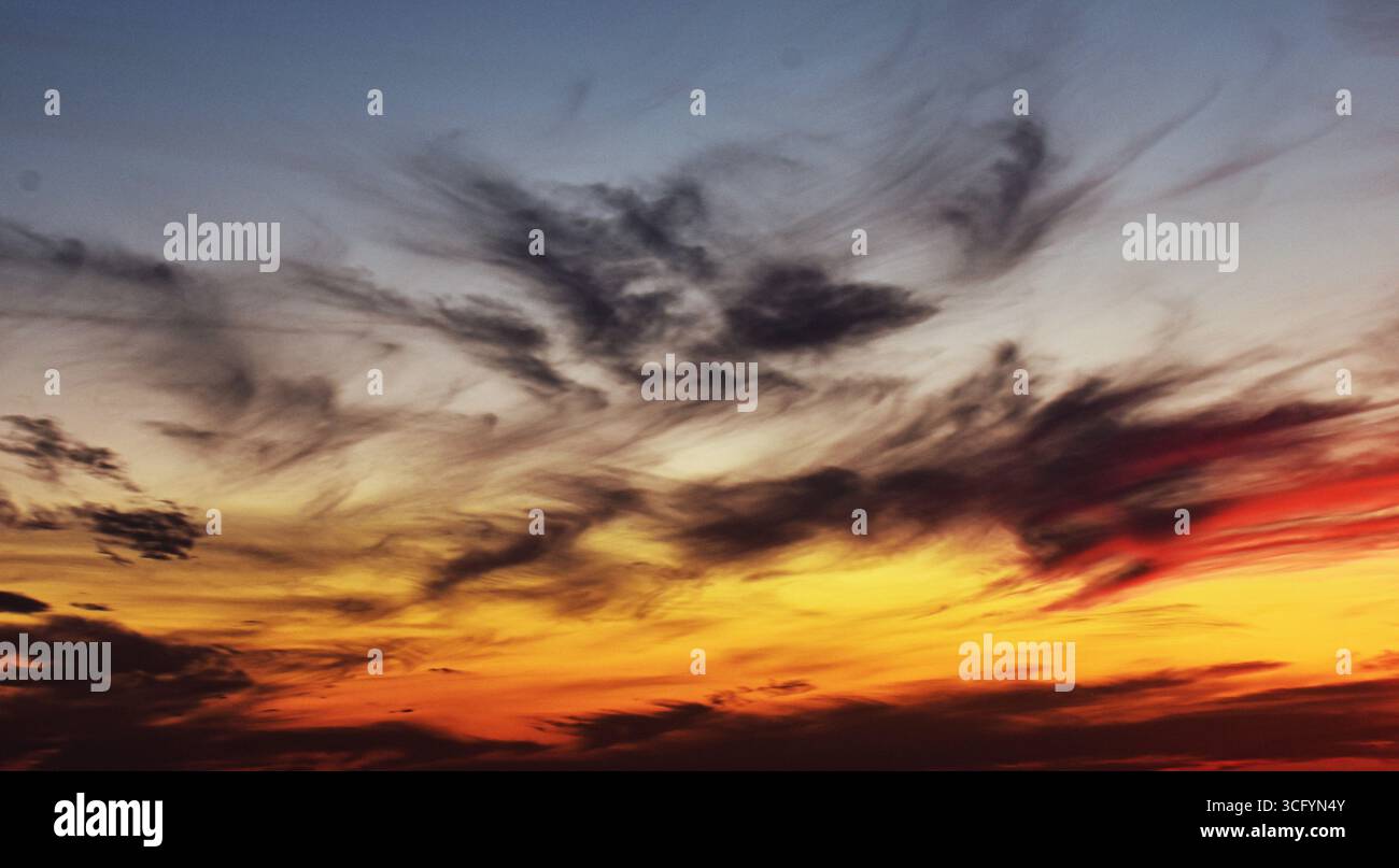 Incantevole panorama del tramonto con nuvole chiare e colori radiosi, che offre un'atmosfera tranquilla e naturale per progetti visivi creativi. Foto Stock