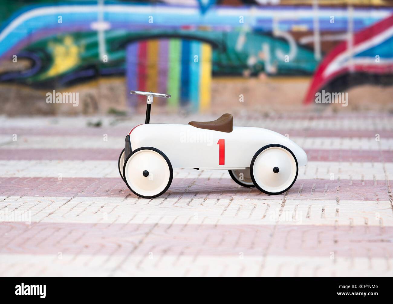 L'auto giocattolo classica presenta un design minimalista, abbinato a vivaci graffiti, creando un'atmosfera divertente e artistica Foto Stock